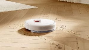 Robot aspirador limpiando huellas y residuos sobre suelo de madera
